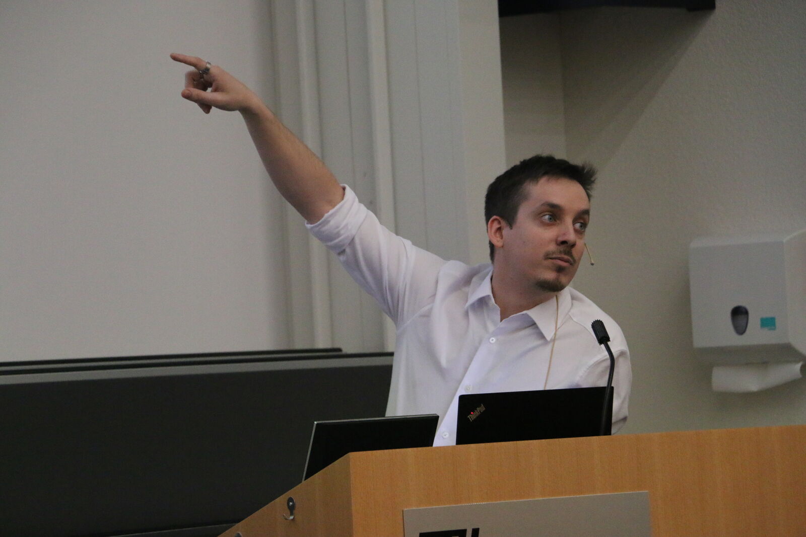 A speaker pointing at the screen during his talk