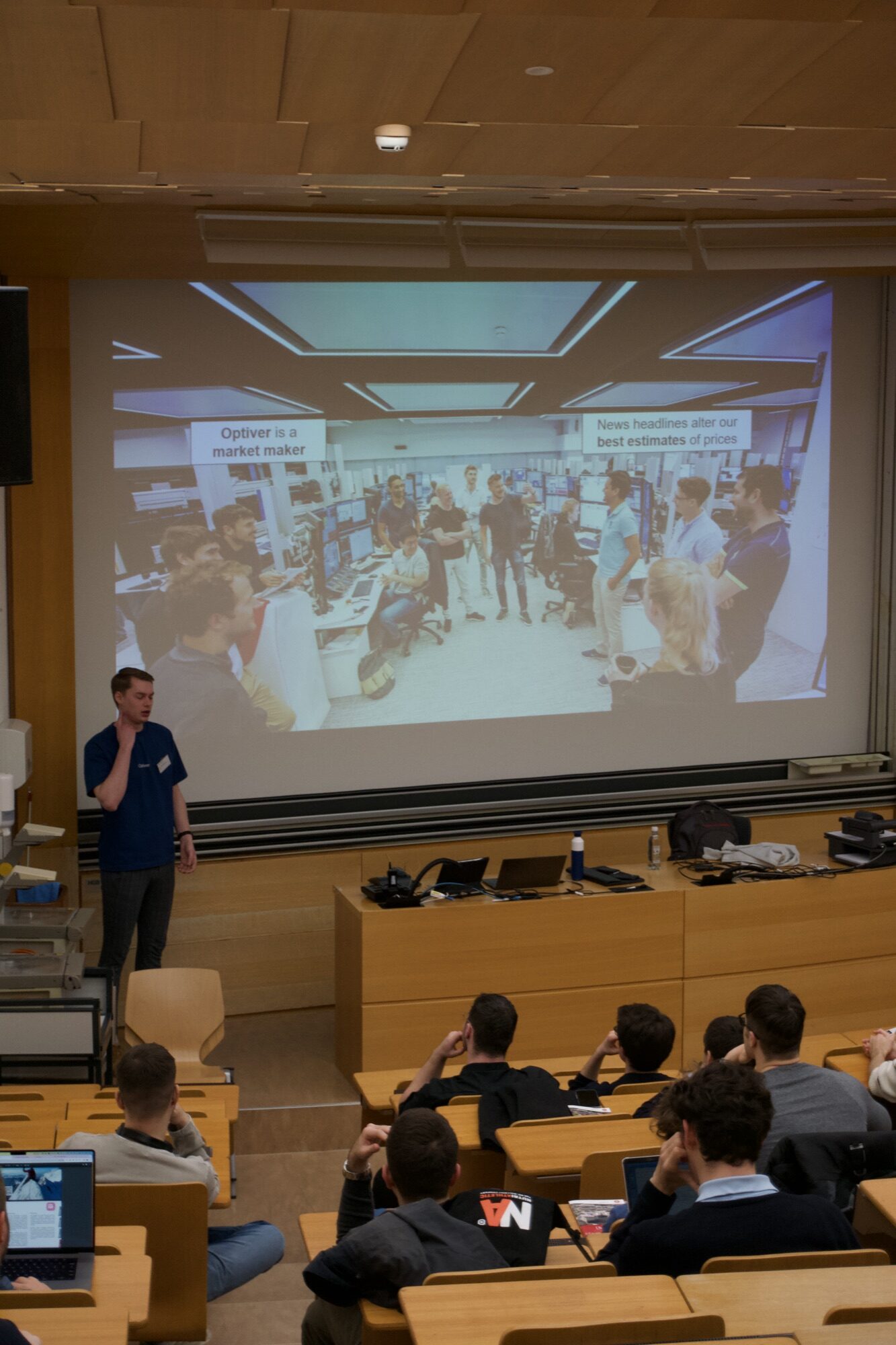 An Optiver speaker in front of a full lecture hall